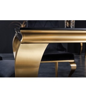 Piękny stół z czarnym blatem na złotych nogach do salonu urządzonego w stylu glamour.