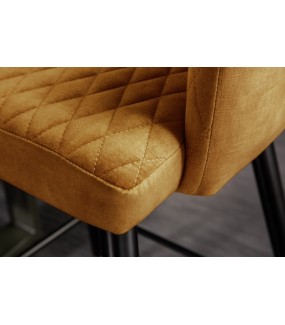 Hoker z siedziskiem w kolorze musztardowym oraz metalową podstawą do eleganckiego salonu.
